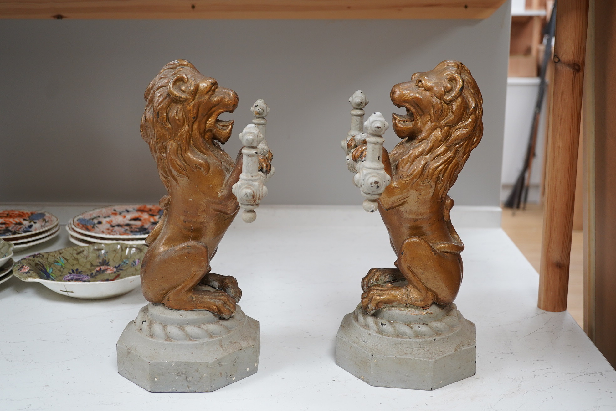 A pair of cast iron fire dogs in the form of triumphant lions, painted, 38cm high, 23cm wide. Condition - fair